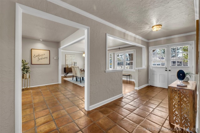 tiled entryway featuring ornamental molding, baseboards, a textured wall, and a textured ceiling