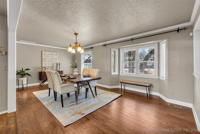 dining area featuring hardwood / wood-style floors, visible vents, crown molding, a chandelier, and a textured ceiling