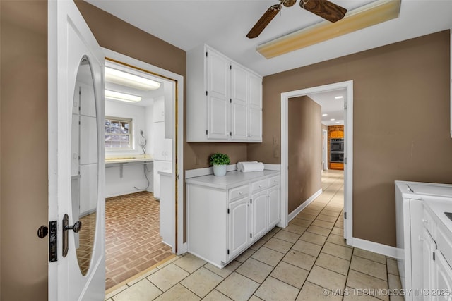 interior space with white cabinets, light countertops, washing machine and clothes dryer, baseboards, and ceiling fan