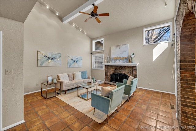 living area with a ceiling fan, a textured wall, rail lighting, baseboards, and a brick fireplace