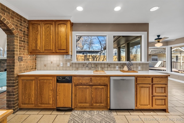 kitchen with a sink, brown cabinets, light tile patterned flooring, dishwasher, and light countertops