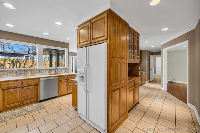kitchen with dishwasher, a sink, crown molding, glass insert cabinets, and white refrigerator with ice dispenser