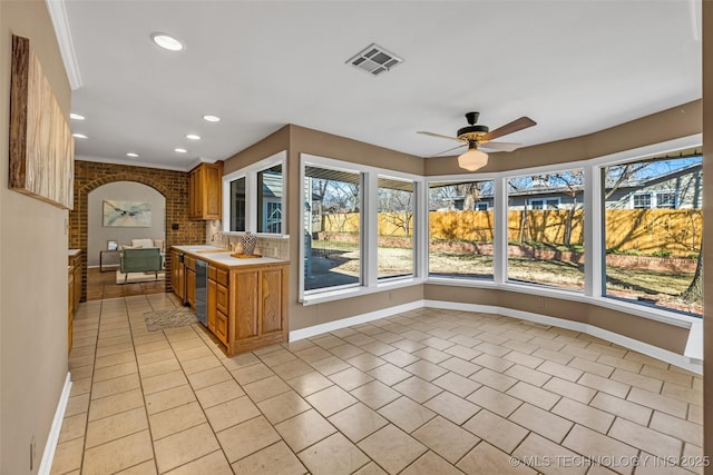 unfurnished sunroom featuring arched walkways, plenty of natural light, visible vents, and a sink