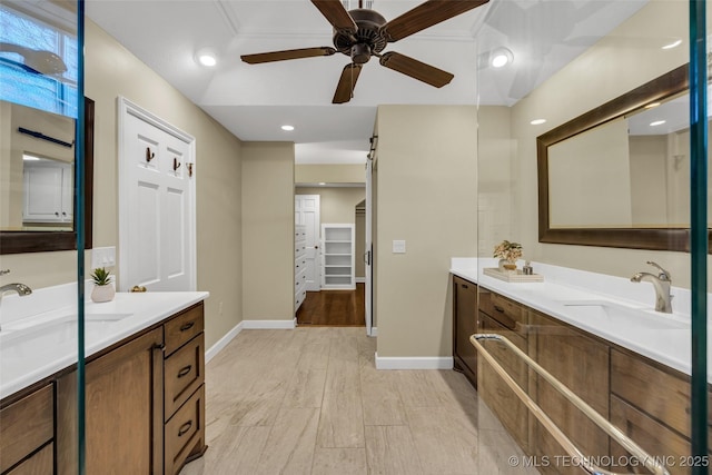full bath featuring two vanities, baseboards, ceiling fan, and a sink