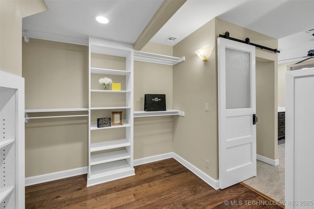 spacious closet with a barn door, wood finished floors, and visible vents