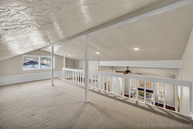 additional living space with a textured ceiling, vaulted ceiling, carpet, a ceiling fan, and a fireplace