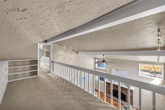 hall featuring track lighting, carpet, and a textured ceiling