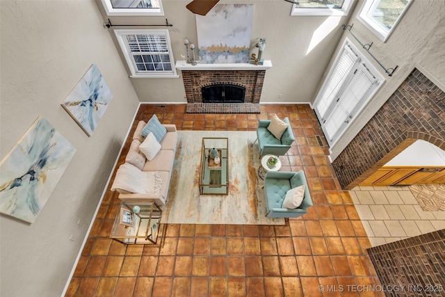 living area featuring a brick fireplace and a high ceiling