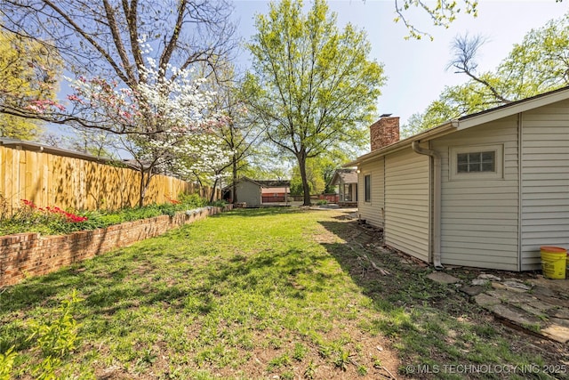 view of yard with a fenced backyard, an outdoor structure, and a shed