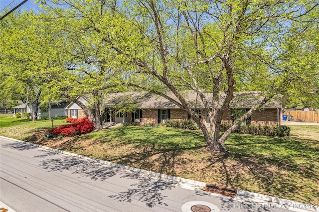 view of front of property with brick siding, fence, and a front yard