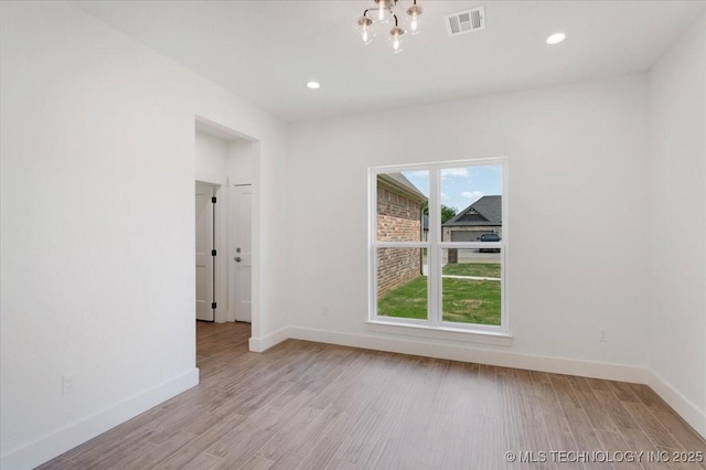unfurnished room with visible vents, light wood finished floors, and baseboards