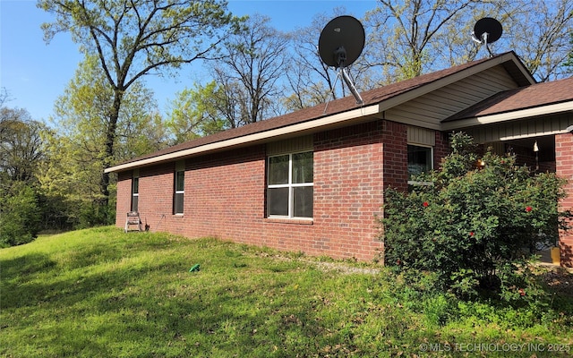 view of side of property with brick siding and a lawn