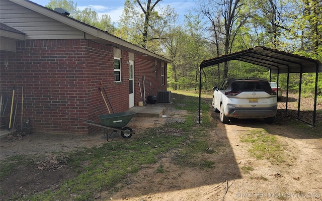 view of home's exterior with a detached carport, driveway, brick siding, and central air condition unit