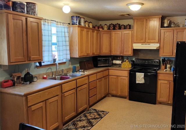 kitchen with a sink, visible vents, light countertops, under cabinet range hood, and black appliances