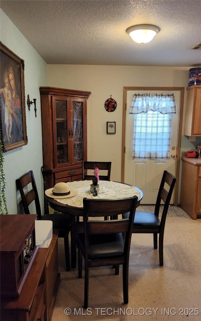 dining area featuring a textured ceiling and visible vents