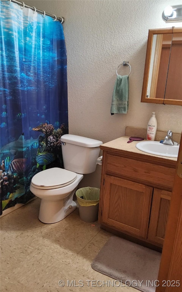 bathroom featuring toilet, a textured wall, vanity, and a shower with shower curtain