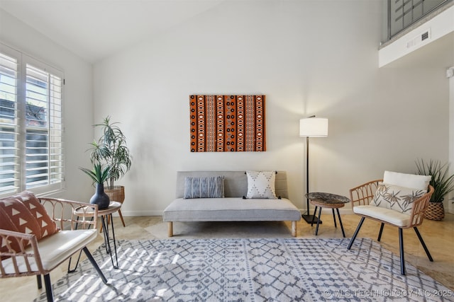 living area featuring baseboards, visible vents, and high vaulted ceiling