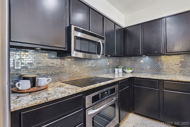 kitchen featuring light stone counters, tasteful backsplash, dark cabinetry, and stainless steel appliances