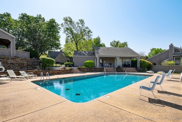 community pool with fence and a patio