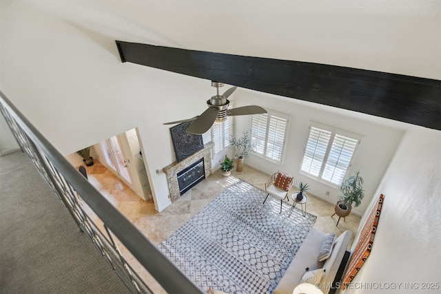 living area with ceiling fan, a high ceiling, light carpet, and a fireplace