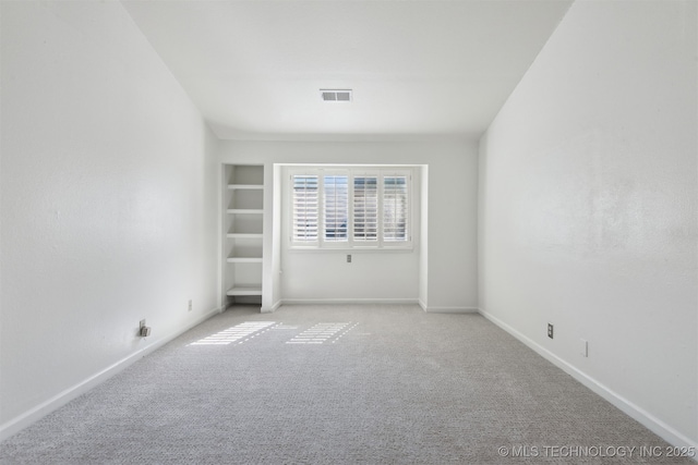 carpeted spare room featuring baseboards and visible vents