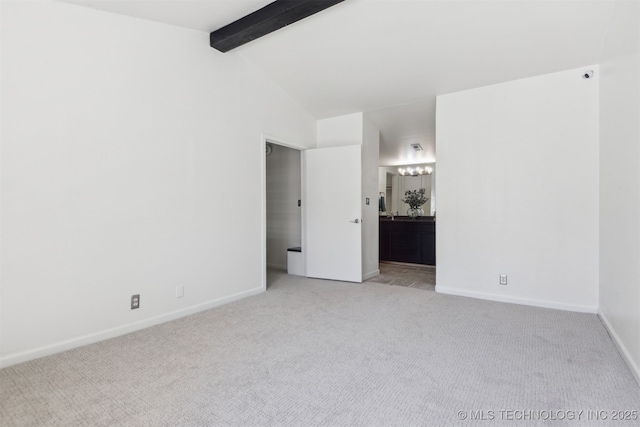 unfurnished bedroom with ensuite bath, light carpet, vaulted ceiling with beams, and baseboards