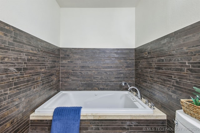 bathroom with tile walls, a garden tub, and toilet