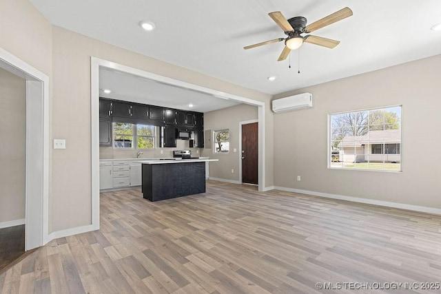 401 S Brewer St, Vinita, OK 74301 - kitchen with light wood finished floors, dark cabinets, light countertops, baseboards, and a wall mounted AC