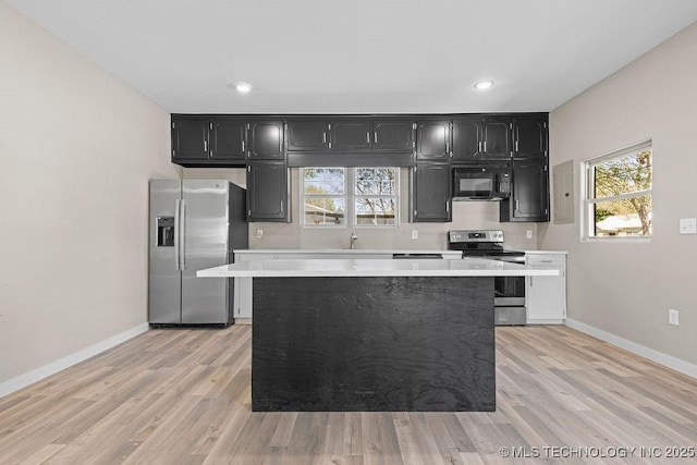 401 S Brewer St, Vinita, OK 74301 - kitchen with a center island, stainless steel appliances, light countertops, and dark cabinetry