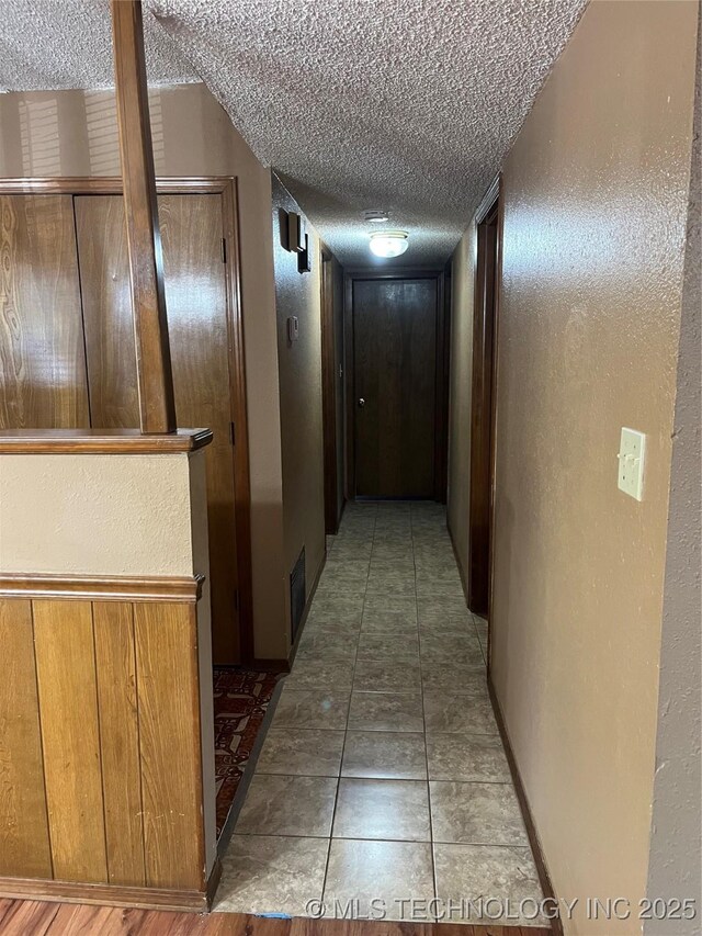 corridor with a textured ceiling and a textured wall