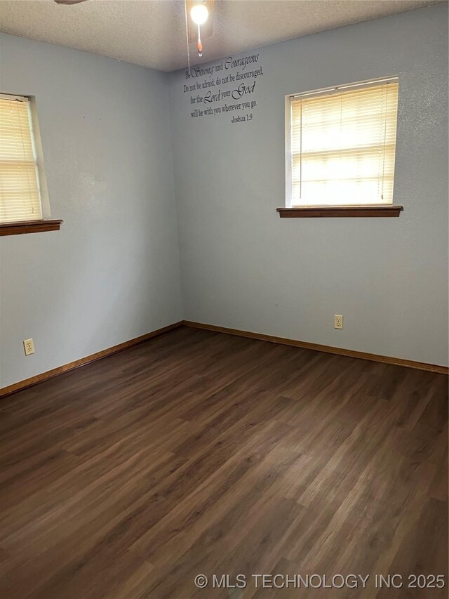 unfurnished room with baseboards, a textured ceiling, ceiling fan, and dark wood-style floors
