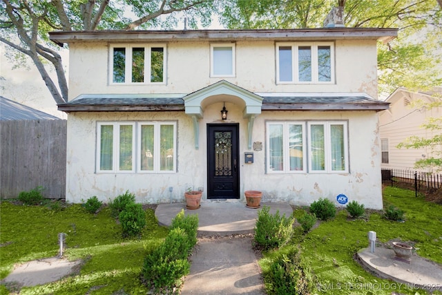 traditional home with fence, a front yard, and stucco siding