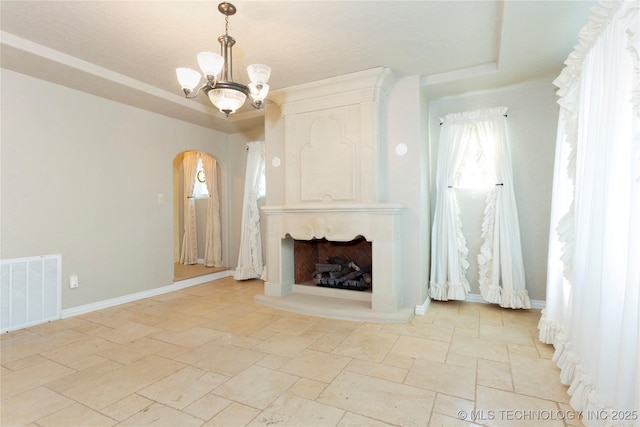 unfurnished living room featuring a high end fireplace, arched walkways, an inviting chandelier, stone tile flooring, and visible vents
