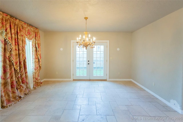 spare room with a chandelier, stone tile flooring, and baseboards