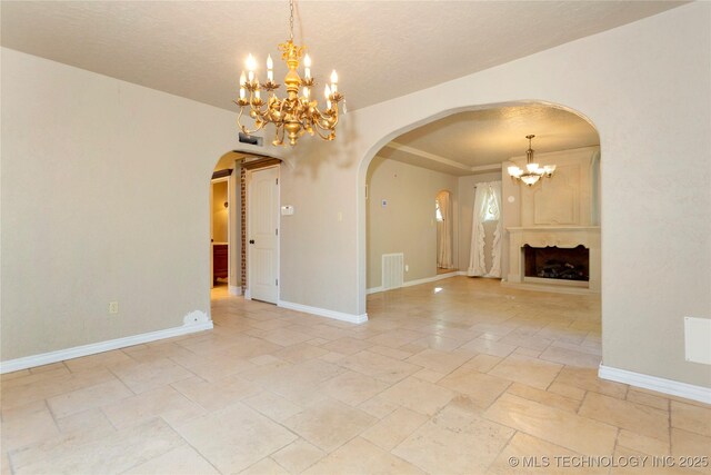 unfurnished room with arched walkways, stone tile floors, baseboards, visible vents, and a notable chandelier