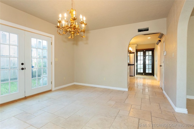 unfurnished room with arched walkways, stone tile flooring, french doors, and a wealth of natural light