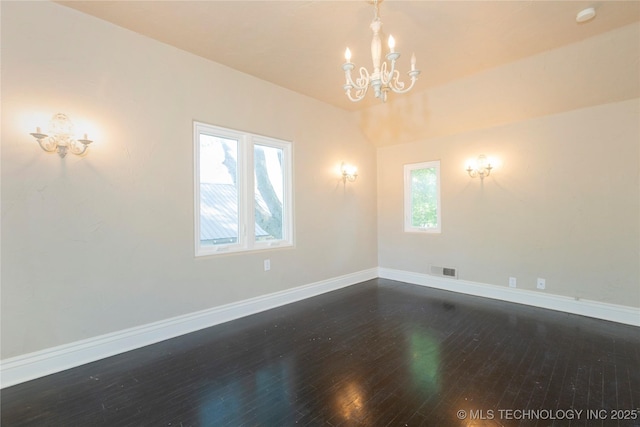 empty room featuring baseboards, a notable chandelier, dark wood-style flooring, and visible vents