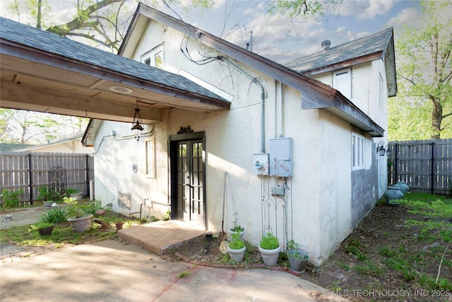 view of exterior entry featuring stucco siding, a patio area, french doors, and fence