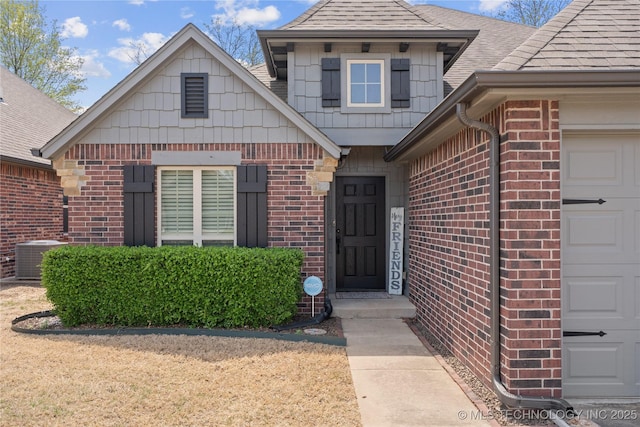3235 Boardwalk Ct, Bartlesville, OK 74006 - entrance to property with central AC unit, brick siding, a shingled roof, and a garage