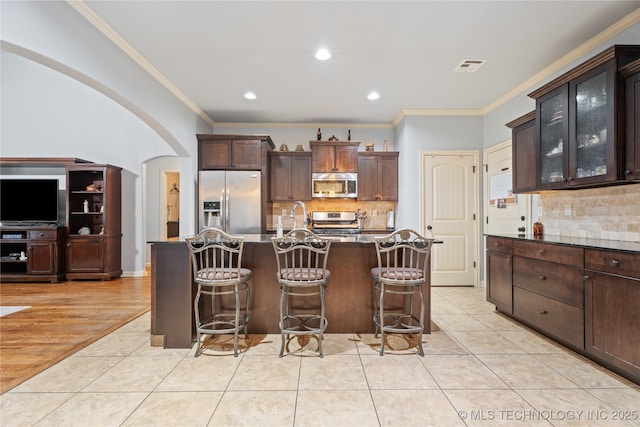 3235 Boardwalk Ct, Bartlesville, OK 74006 - kitchen featuring decorative backsplash, stainless steel appliances, arched walkways, and crown molding