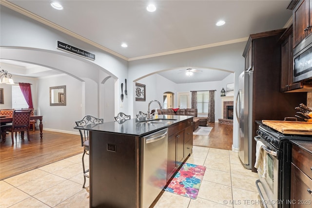 3235 Boardwalk Ct, Bartlesville, OK 74006 - kitchen featuring a sink, light tile patterned flooring, arched walkways, appliances with stainless steel finishes, and open floor plan