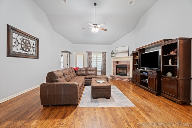 3235 Boardwalk Ct, Bartlesville, OK 74006 - living area with arched walkways, a brick fireplace, wood finished floors, ceiling fan, and high vaulted ceiling