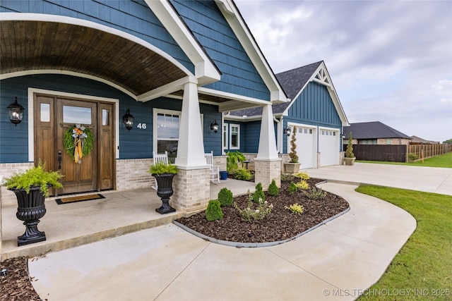 entrance to property featuring fence, board and batten siding, driveway, covered porch, and brick siding