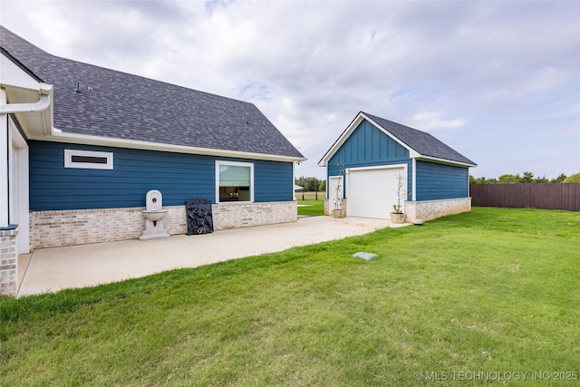 exterior space with a yard, board and batten siding, an outdoor structure, a detached garage, and brick siding