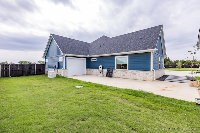 exterior space with a yard, driveway, a shingled roof, and fence