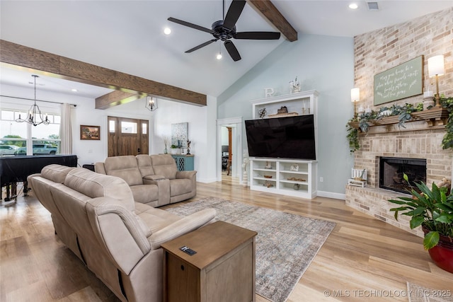 living area featuring wood finished floors, ceiling fan with notable chandelier, lofted ceiling with beams, a fireplace, and recessed lighting