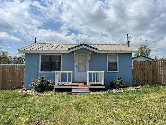 bungalow featuring metal roof, a front lawn, and fence