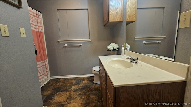 506 S Delaware Ave, Okmulgee, OK 74447 - full bathroom with stone finish floor, a textured wall, toilet, vanity, and baseboards