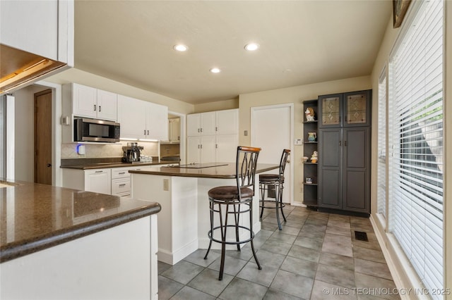 10421 S Richmond Pl, Tulsa, OK 74137 - kitchen with white cabinets, a center island, stainless steel microwave, recessed lighting, and a breakfast bar
