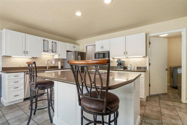 10421 S Richmond Pl, Tulsa, OK 74137 - kitchen with a kitchen breakfast bar, decorative backsplash, white cabinetry, appliances with stainless steel finishes, and a kitchen island